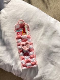 a pink and white crocheted bookmark laying on top of a bed next to a pillow