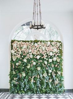 an artificial flower wall in front of a chandelier