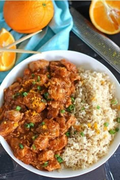 a white bowl filled with rice and meat next to an orange slice on the side