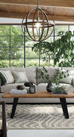 a living room with a couch, coffee table and potted plants on the floor