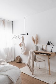 a bedroom with a bed, desk and hanging clothes on the rack in it's corner