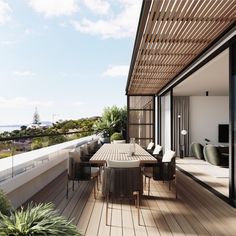 an outdoor dining table and chairs on a wooden deck overlooking the ocean with greenery