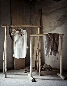 an old room with clothes hanging on wooden poles and two coats racks next to it