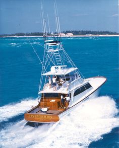 a white and brown boat in the ocean with people on it's back end