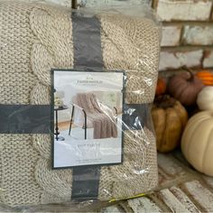 a package of blankets sitting on top of a table next to pumpkins and gourds