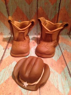 two brown boots and a hat sitting on top of a wooden floor next to each other