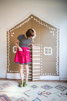 a woman standing in front of a cardboard house