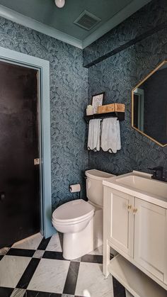 a white toilet sitting in a bathroom next to a black and white checkered floor