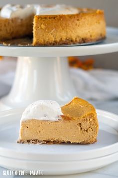 a slice of pumpkin cheesecake on a white plate with the rest of the pie in the background