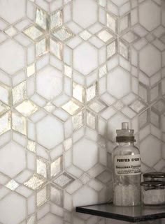 a white tiled wall next to a shelf with some jars on it and a bottle in the corner