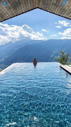 a person sitting in the middle of a pool with mountains in the backgroud