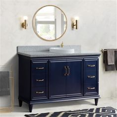 a white sink sitting under a mirror next to a blue cabinet with gold handles and drawers