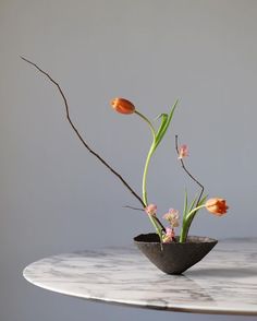 a vase with some flowers in it on top of a marble table and gray wall