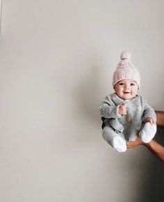 a man holding a baby wearing a pink hat and grey sweater with white socks on