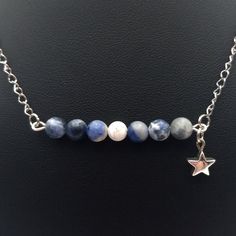 a necklace with a star charm on the front and two different colored beads hanging from it