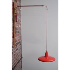 a red light hanging from the side of a brick wall next to a white wall