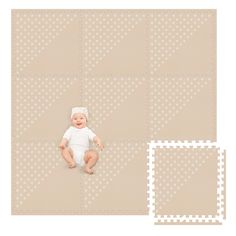 a baby laying on top of a floor next to two squares