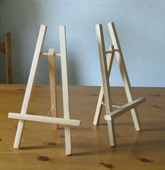 two small wooden easels sitting on top of a table next to each other,