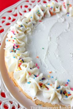 a cake with white frosting and sprinkles on a doily plate