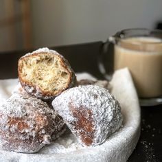 powdered sugar covered doughnuts on a plate next to a glass of milk