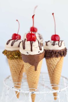 three ice cream cones with cherries on top