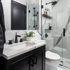 a white toilet sitting next to a walk in shower under a bathroom mirror above a sink