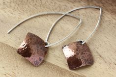 Hand formed sterling silver open hoops in an almond shape with dangling hammered copper squares, in a diamond shape. These light weight copper earrings have a light patina that brings out an earthy warm quality. Modern and a bit rustic! These earring are 1 3/4 inches (4.5 cm) long in the front, the back hangs a bit longer.  The copper square is 5/8 x 5/8 inches (16 mm) All earrings come with clear earring stoppers. All of my designs are created by me, including all the metal components like ear Handmade Modern Copper Jewelry, Modern Handmade Copper Jewelry, Artisan Hammered Rose Gold Jewelry, Minimalist Hammered Copper Jewelry, Artisan Rose Gold Hammered Jewelry, Modern Nickel-free Copper Jewelry, Everyday Hammered Copper Earrings, Hammered Silver Copper Earrings, Hammered Copper Drop Earrings