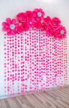 pink flowers are hanging on the wall in front of a white wall with polka dots