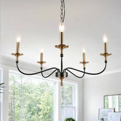 a chandelier with five lights hanging from the ceiling in a living room next to a window