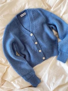 a blue sweater laying on top of a bed