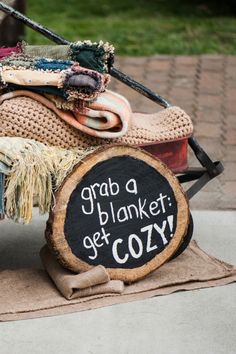 there is a sign that says grab a blanket get cozy next to a wheelbarrow