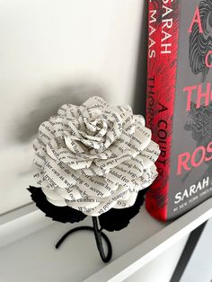 a book is sitting on a shelf next to a fake rose