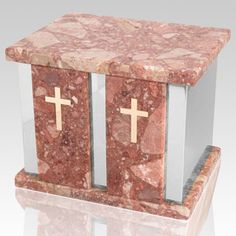 a red marble box with two crosses on the front and one at the top, sitting on a reflective surface