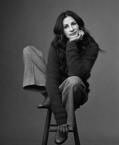 a black and white photo of a woman sitting on a stool