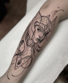 a woman's arm with a black and white tattoo design on the left forearm