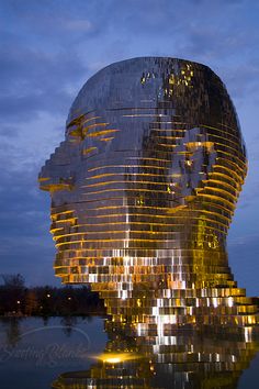 a very large building that has some kind of face on it's side in front of the water