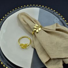 a plate with a napkin and a gold ring on it, sitting on a table