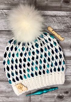 a white and blue knitted hat with a pom - pom on top