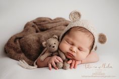 a baby sleeping with a teddy bear on top of it's head and wearing a knitted hat