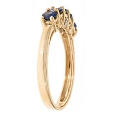 a yellow gold ring with two blue stones on the side and an oval shaped diamond in the center