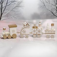 a group of wooden toys sitting next to each other on a snow covered ground with trees in the background