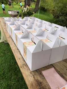 several boxes are lined up on a table in the grass with people standing around them