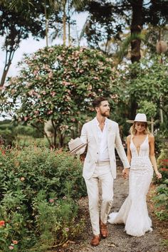 a bride and groom walking down a path holding hands