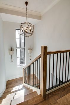 an empty staircase with wooden handrails and chandelier