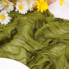 some flowers are sitting on a table and green fabric is draped over the table cloth