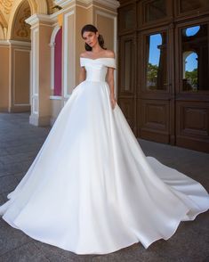 a woman in a white wedding dress posing for the camera with her hands on her hips