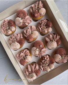 twelve cupcakes with pink icing in a box