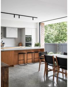 an open kitchen and dining area with wooden furniture