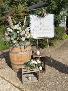 a welcome sign next to a wooden barrel filled with flowers