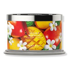 a candle that is sitting in front of a white background with oranges and pomegranates on it